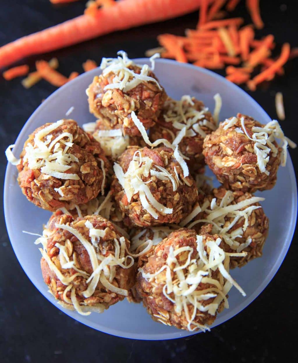 carrot cake energy bites n clear bowl topped with shredded coconut