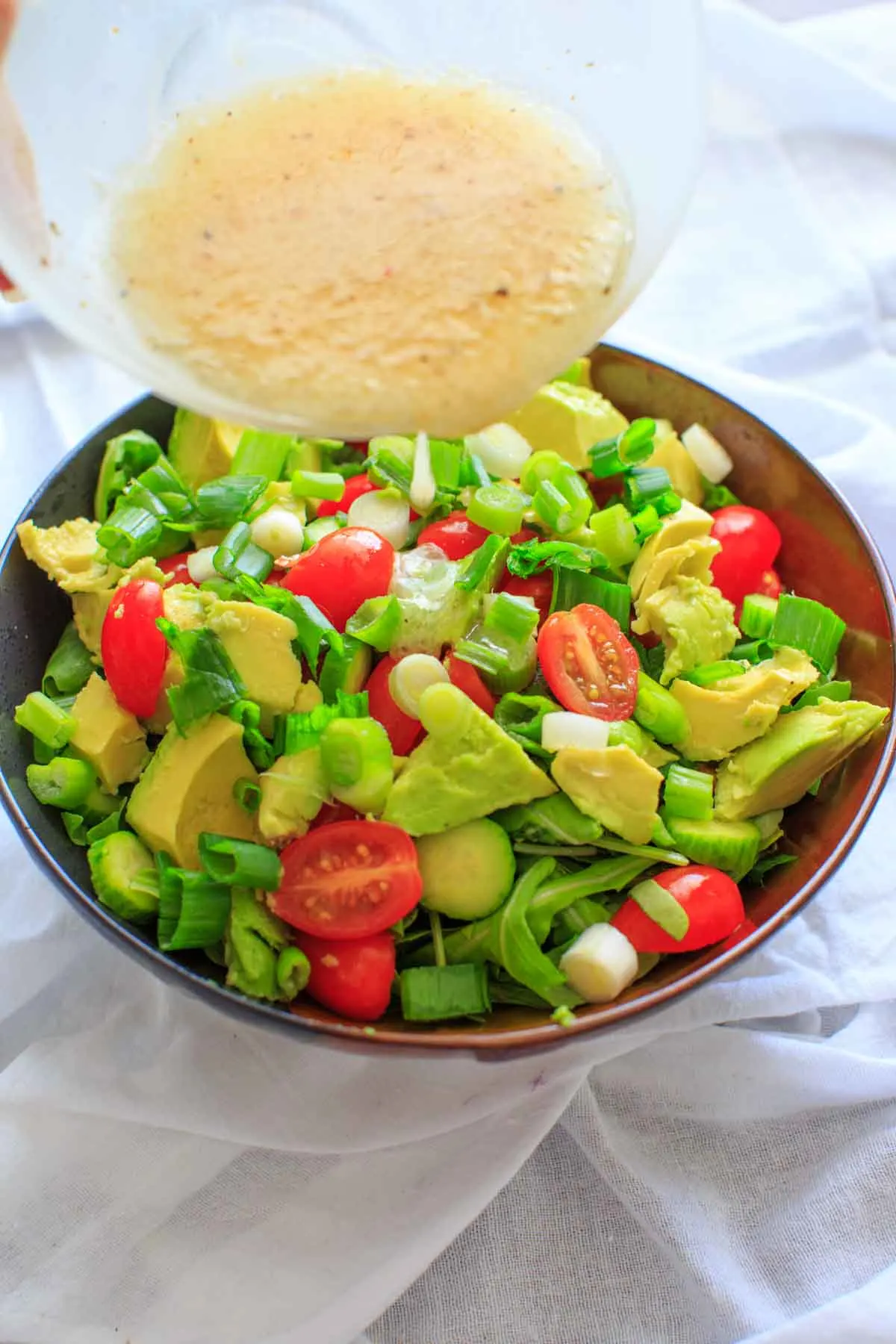 pouring the miso dressing on top of salad