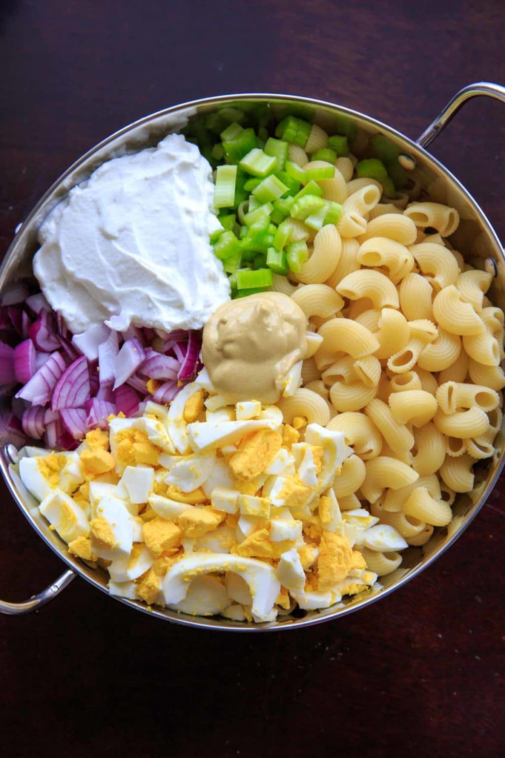 Deconstructed egg salad macaroni with yogurt, pasta, eggs, celery, onion and mustard.