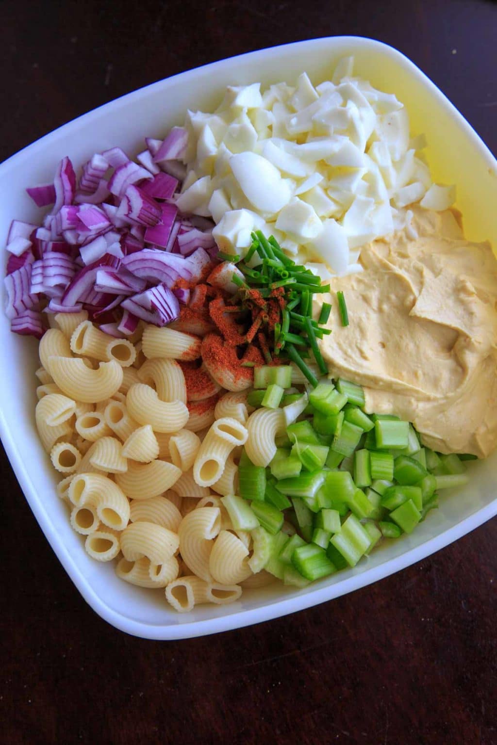Deconstructed deviled egg pasta salad with macaroni, celery, onion, egg white and deviled egg mixture..