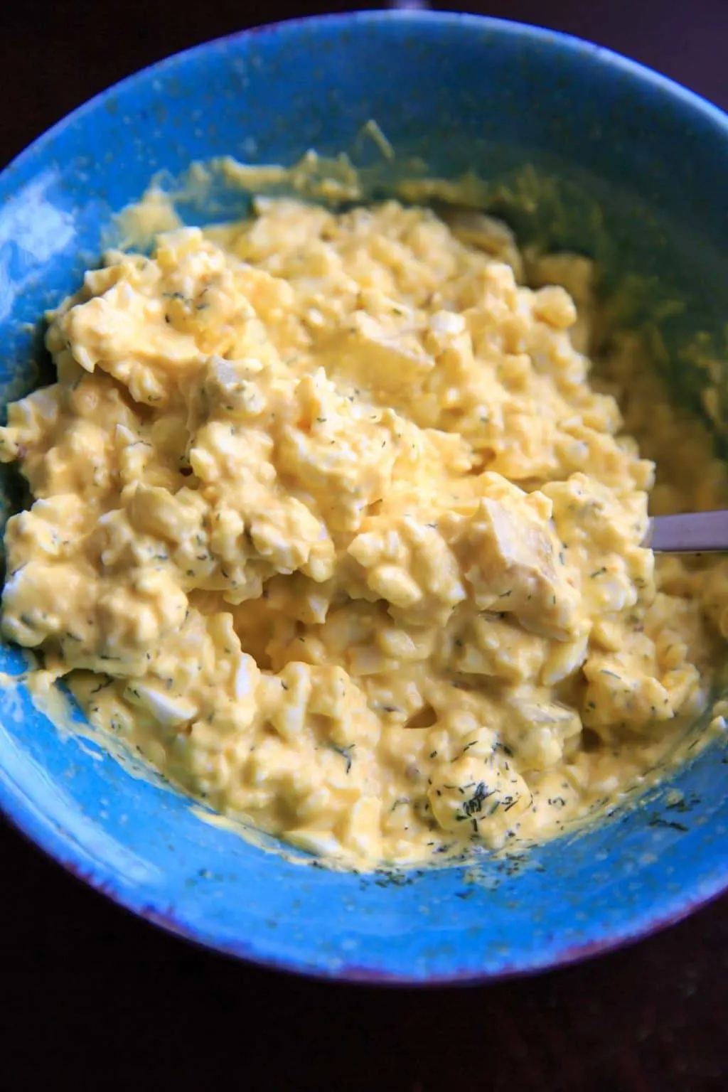 mashed up egg salad in blue bowl