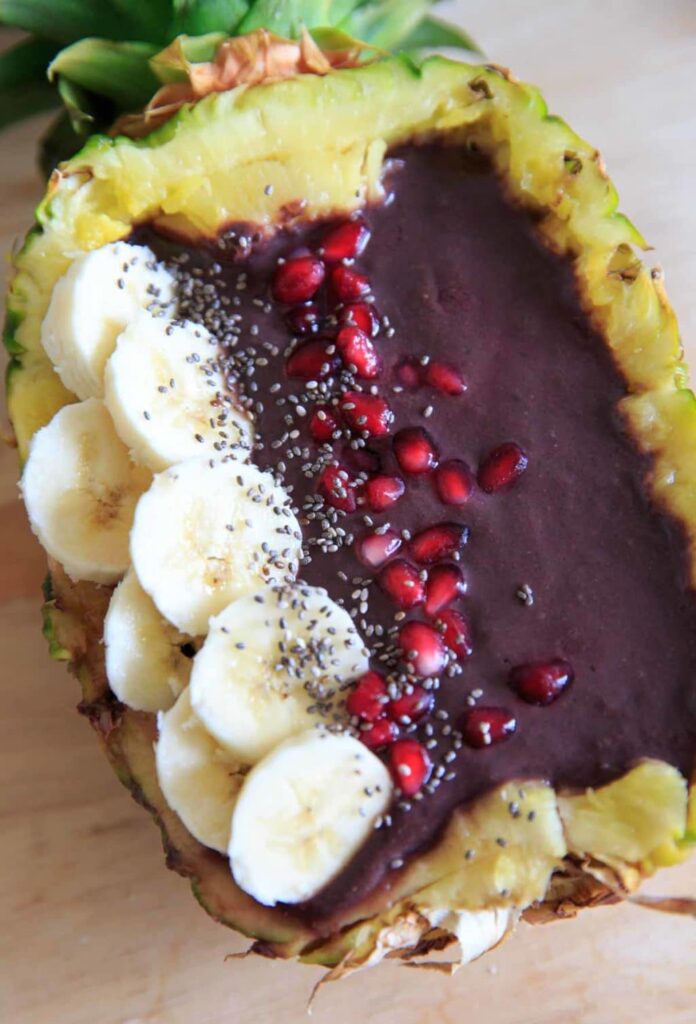 Pineapple Acai Smoothie Bowl or Boat. Pineapple boat with banana, pomegranate arils, and chia seeds.