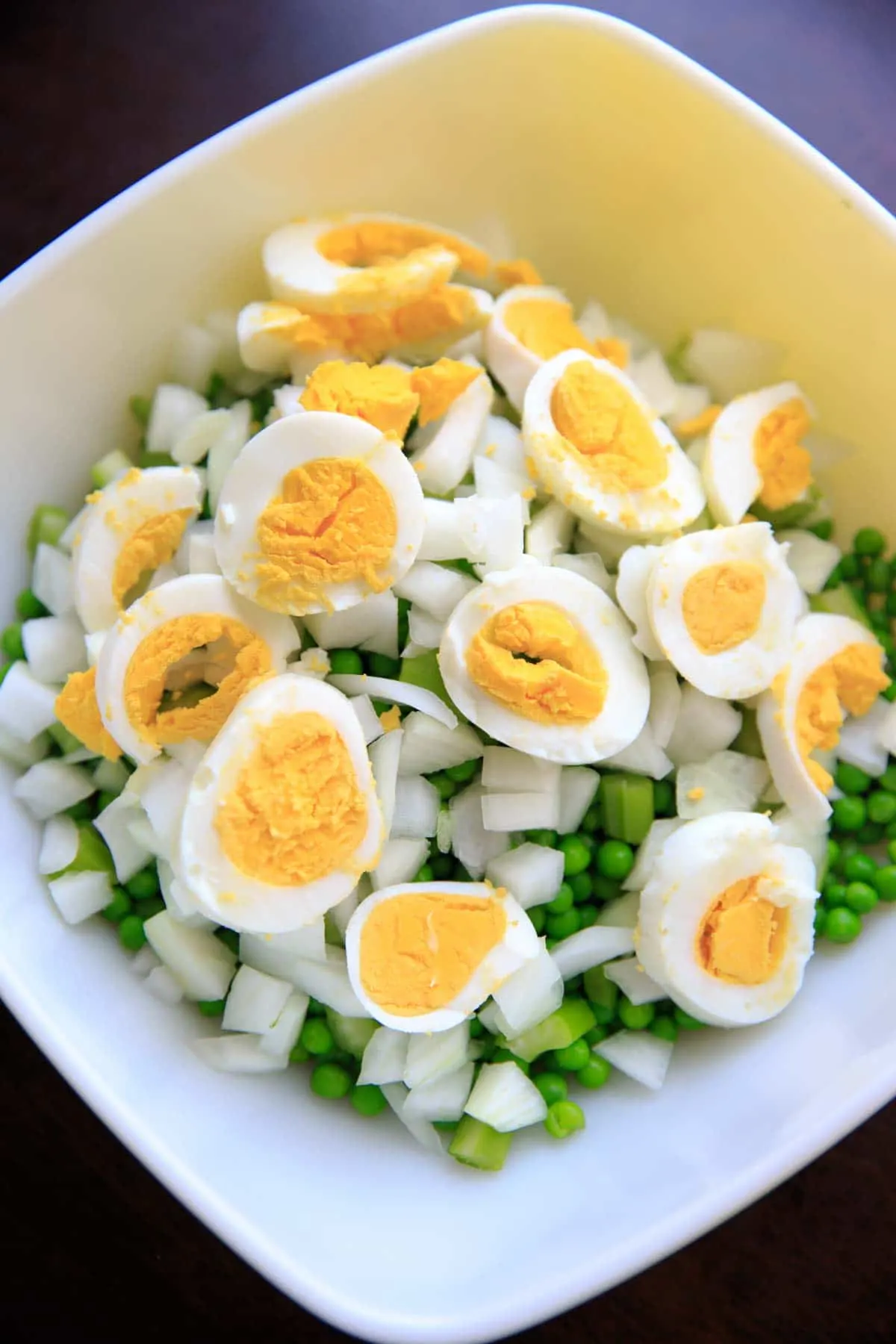 adding sliced hard boiled eggs to the pea salad