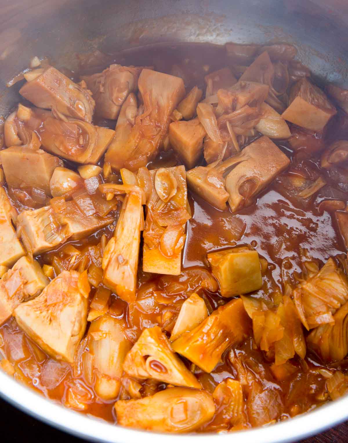 jackfruit cooking in a pot with the bbq sauce, before pulling