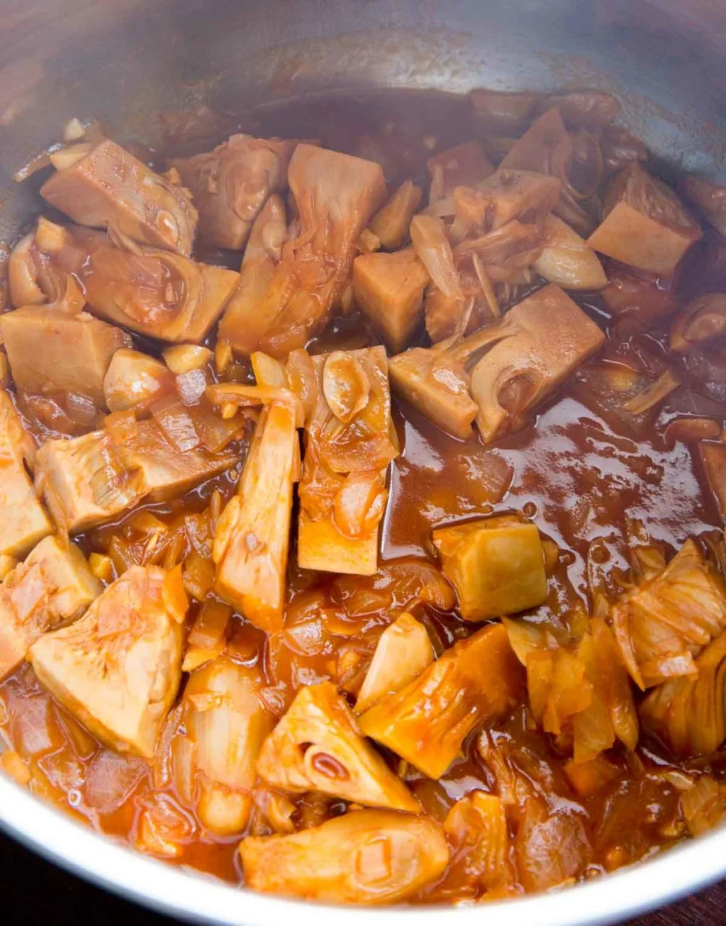jackfruit cooking in a pot with the bbq sauce, before pulling