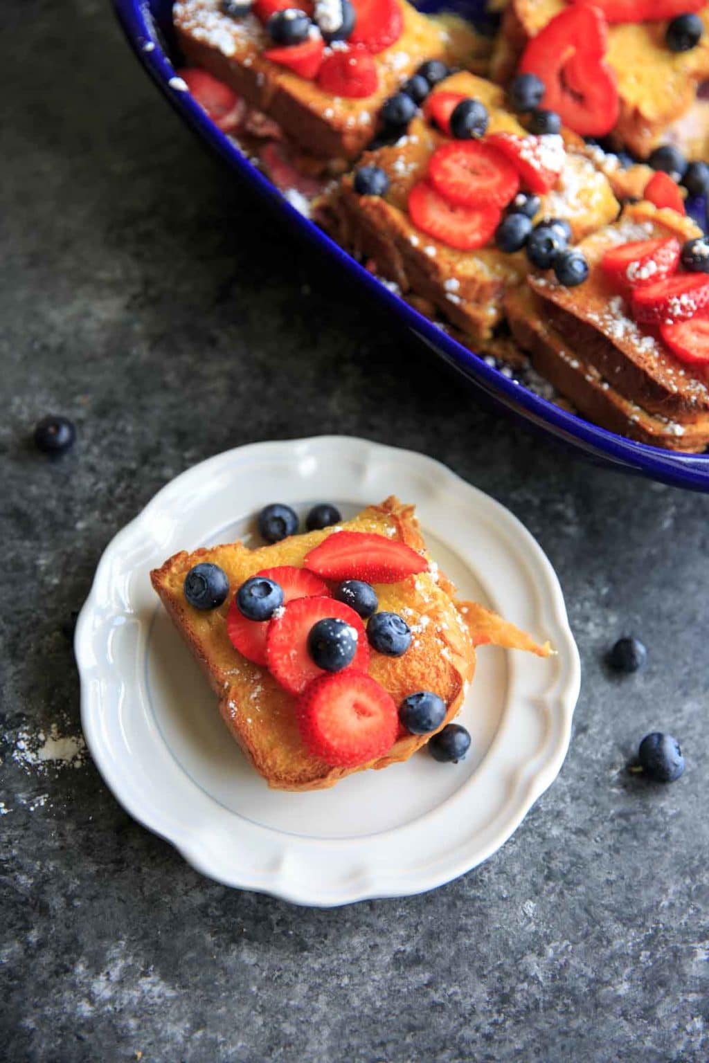 Summer Berry Stuffed French Toast Casserole Bake. Stuffed with cream cheese, fruit jam, strawberries and blueberries and topped with more berries! Serve with a sprinkle of powdered sugar and/or maple syrup if desired. Breakfast or brunch is served! Picture shows one serving of the french toast sandwich.