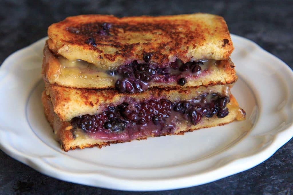 Blackberry Brie Grilled Cheese Sandwich cut in half on white plate