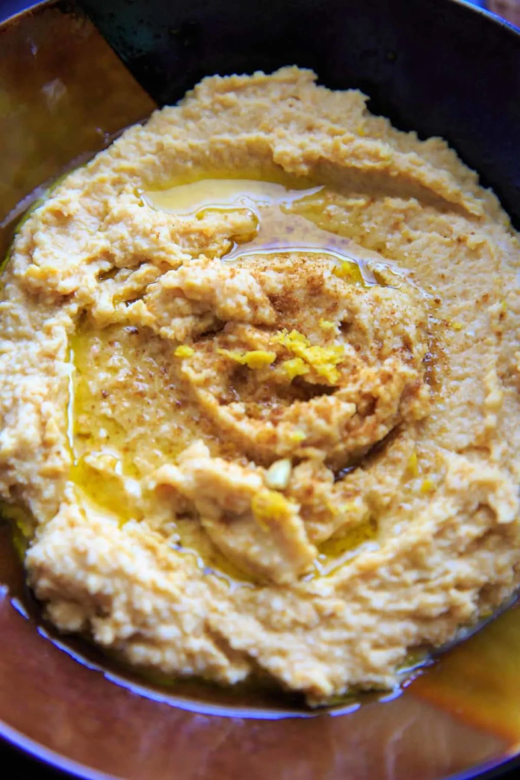 close up of lemon garlic hummus in bowl topped with lemon zest 