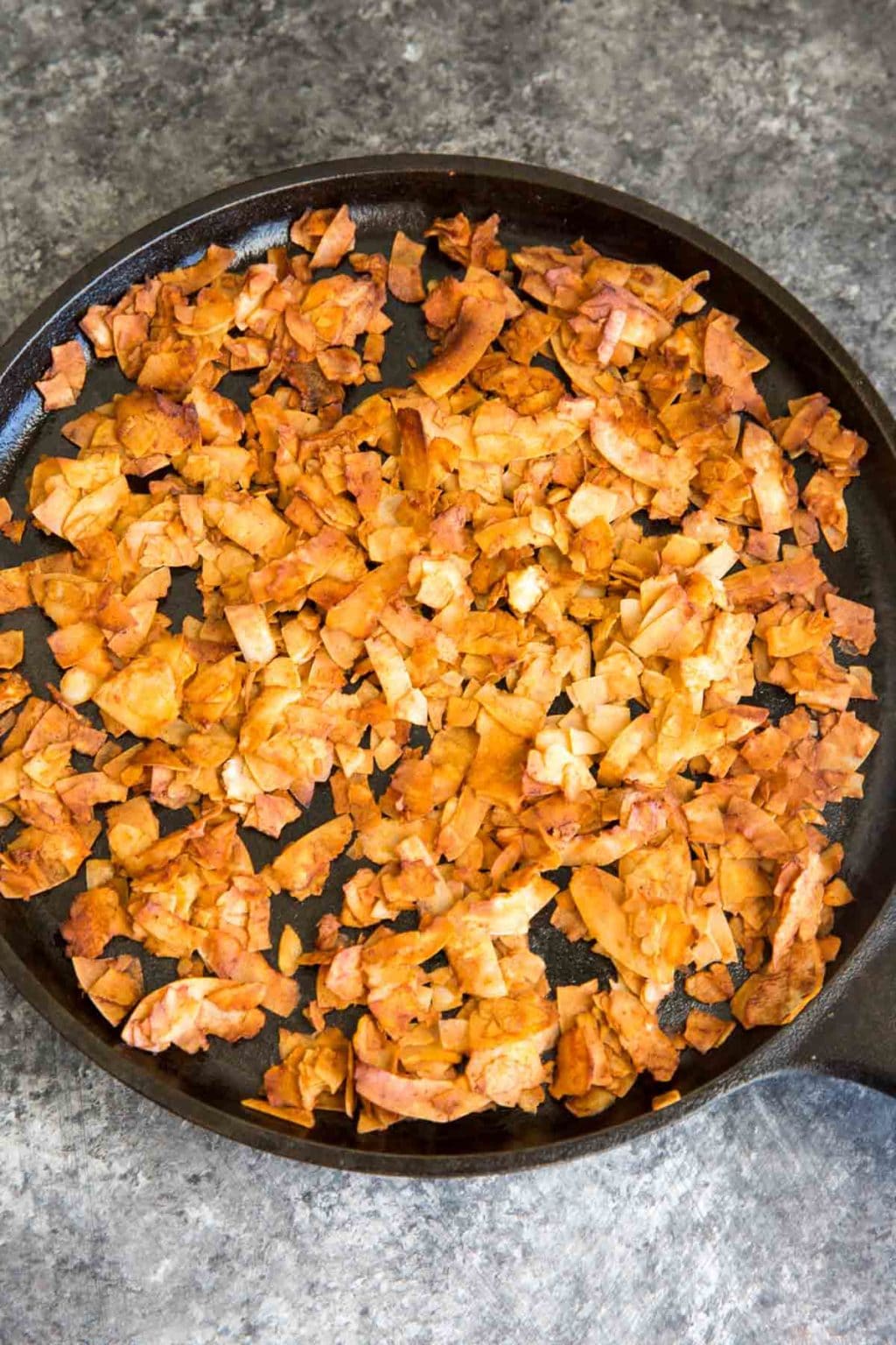 Coconut Chips baked into bacon on cast iron pan