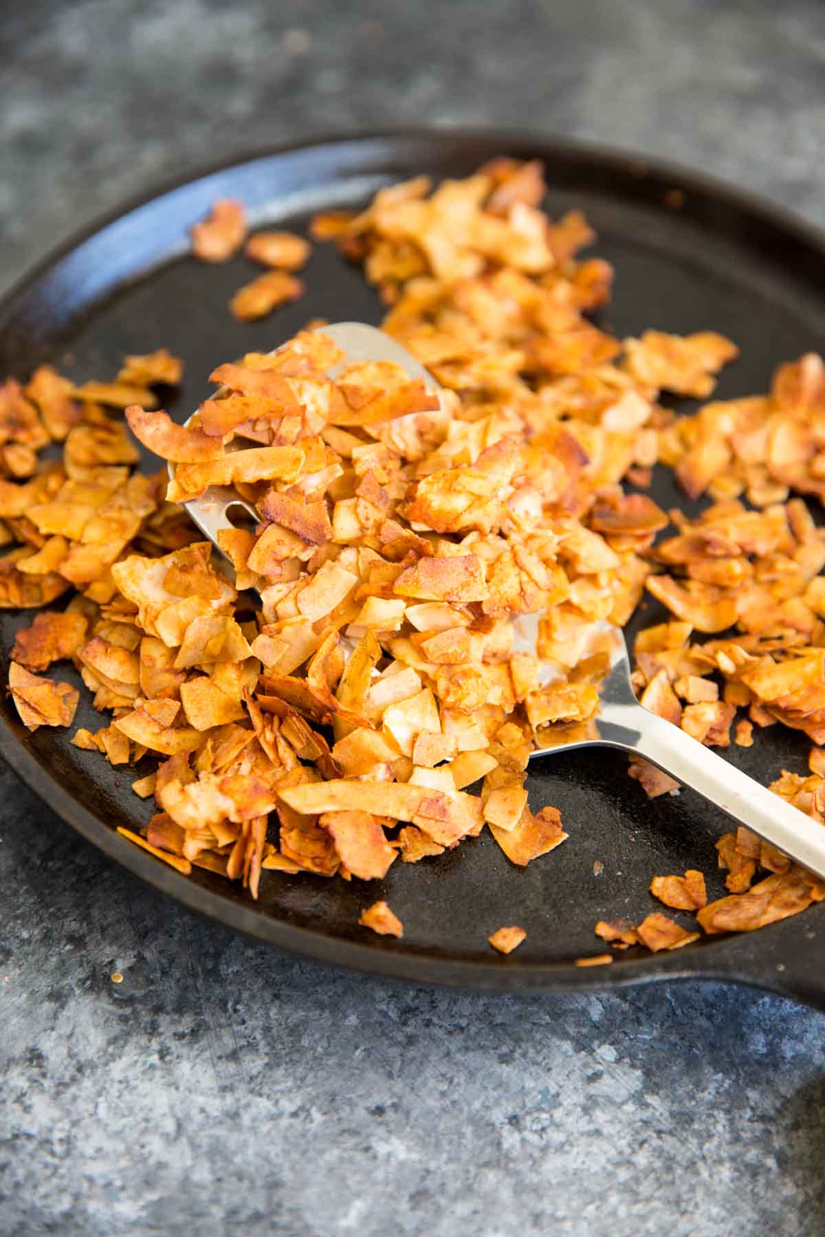 Coconut Flake vegan bacon on cast iron with spatula after cooking