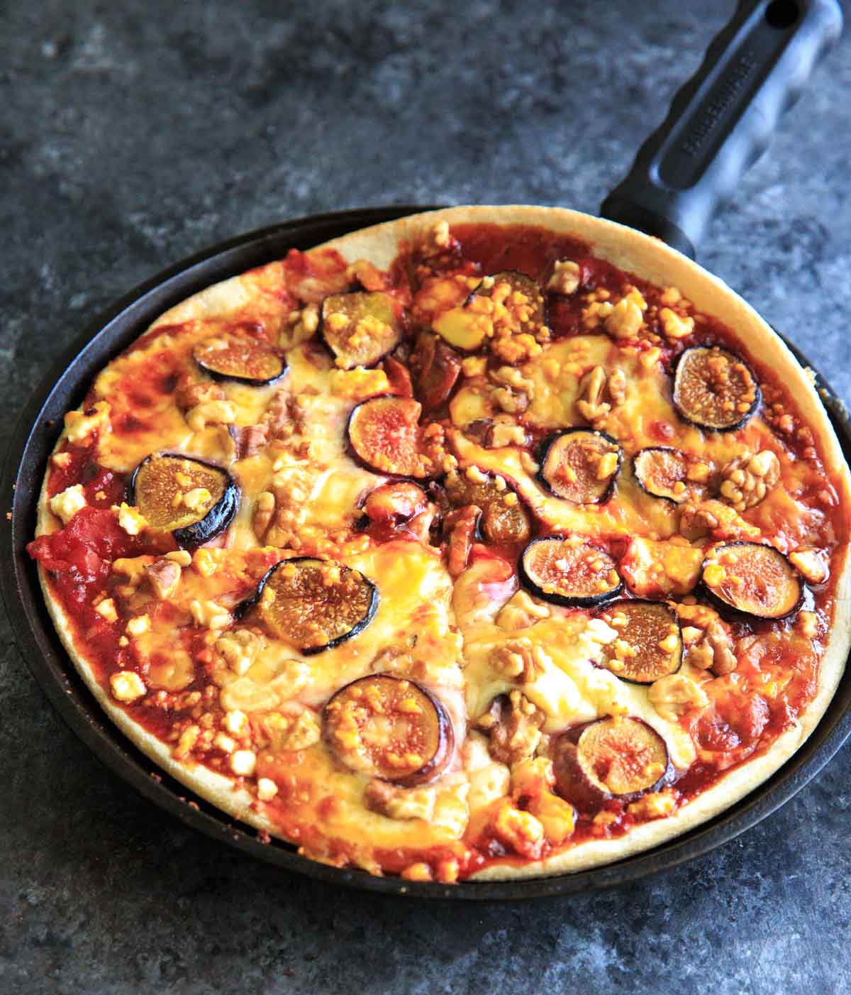 Honey Fig Pizza with Feta Cheese and Walnuts on cast iron cut into 4 pieces