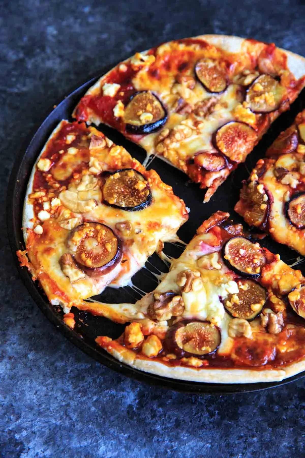 4 pieces of Honey Fig Pizza with cheese stretched out on cast iron