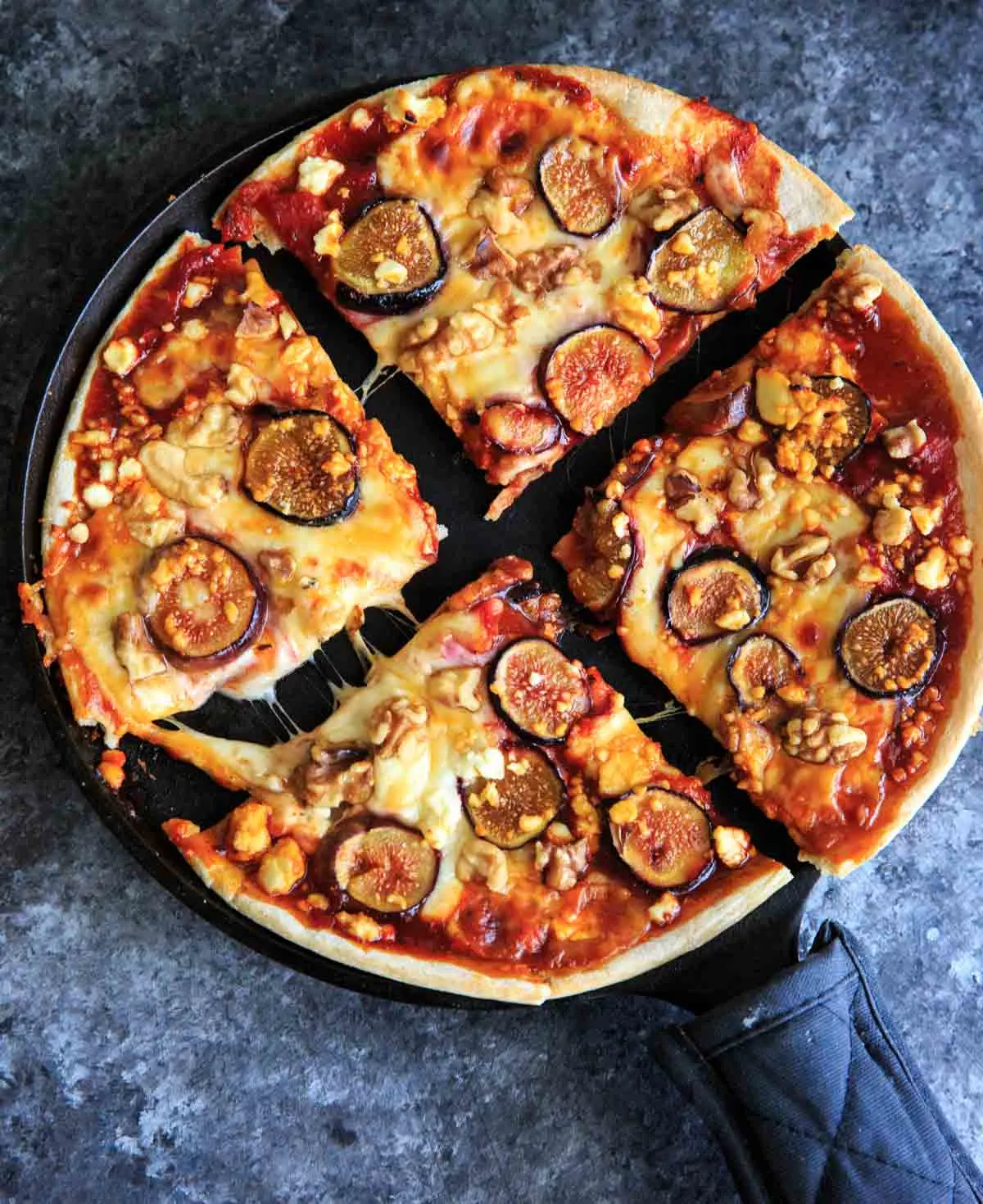 4 pieces of Honey Fig Pizza with cheese stretched out on cast iron pan