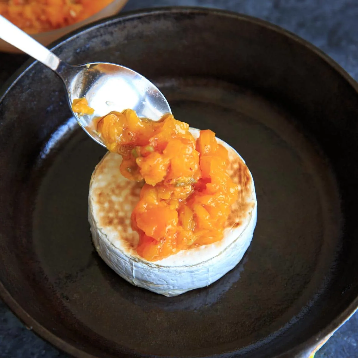 placing cooked peaches on top of brie with spoon