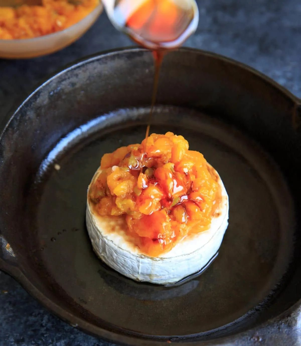 pouring honey on top of peach jalapeno baked brie