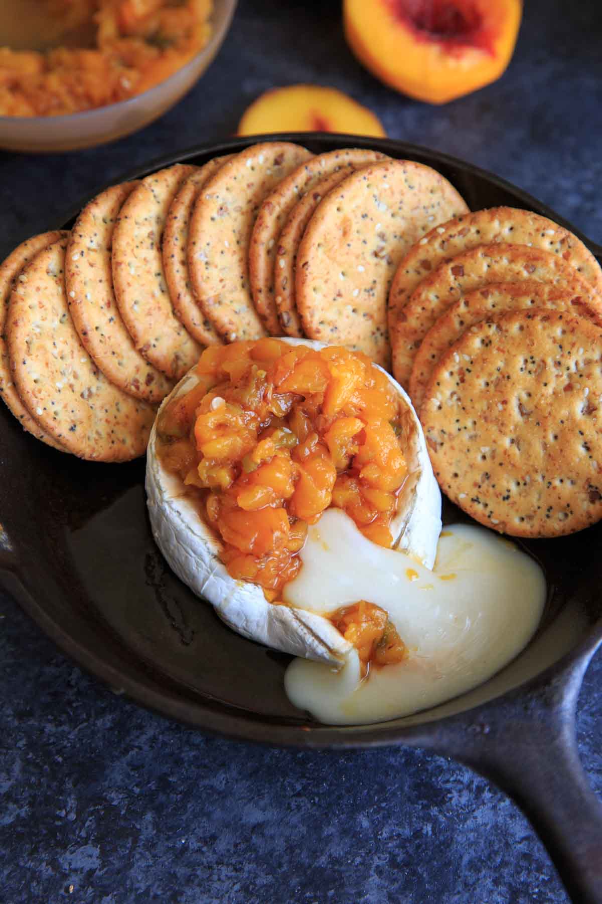 Peach Jalapeno Honey Baked Brie in cast iron with crackers on side