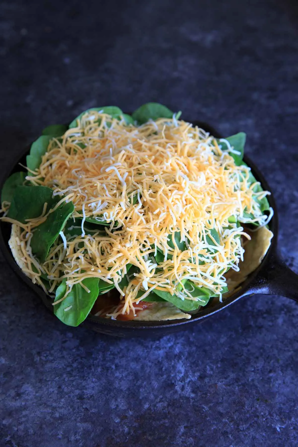 Oven-baked spinach nachos in a cast iron skillet. A great party snack, meal for 2 (or 1!) that has a little extra nutrition with greens.