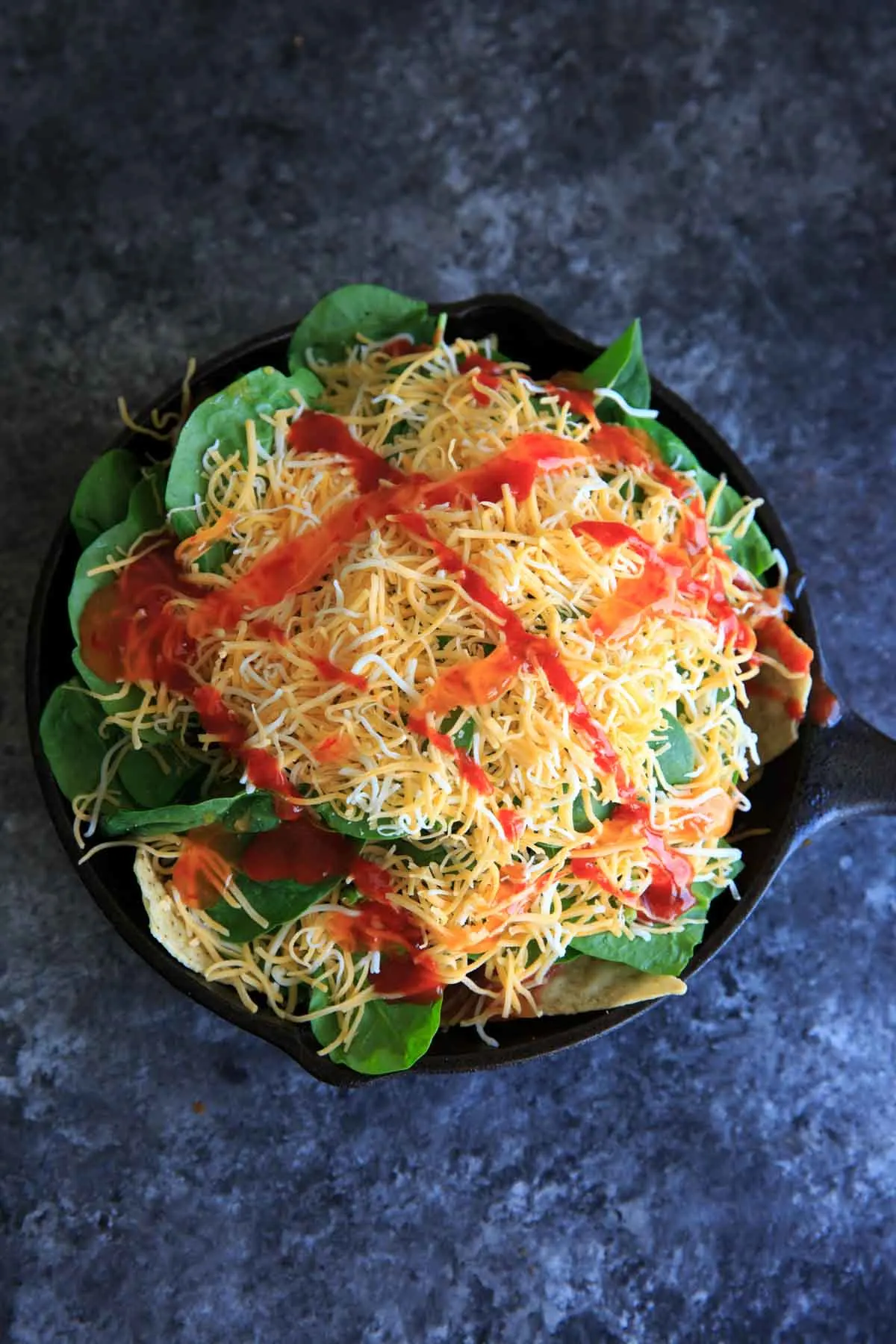 Oven-baked spinach nachos in a cast iron skillet. A great party snack, meal for 2 (or 1!) that has a little extra nutrition with greens.