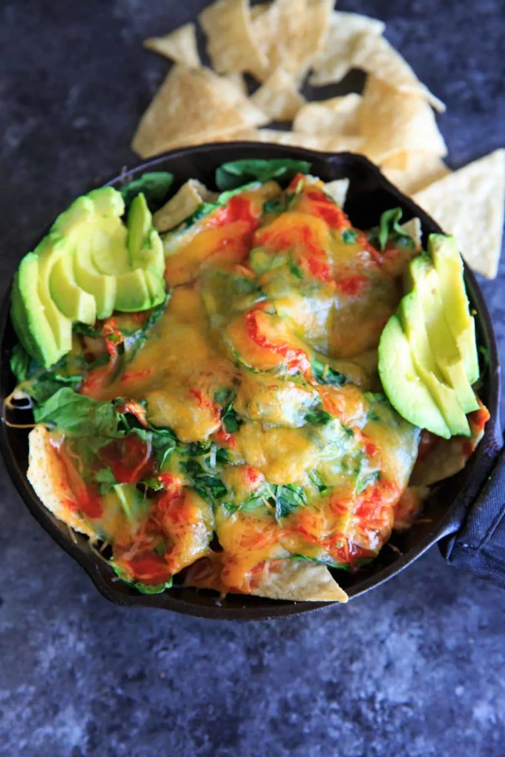 Oven-baked spinach nachos in a cast iron skillet. A great party snack, meal for 2 (or 1!) that has a little extra nutrition with greens.