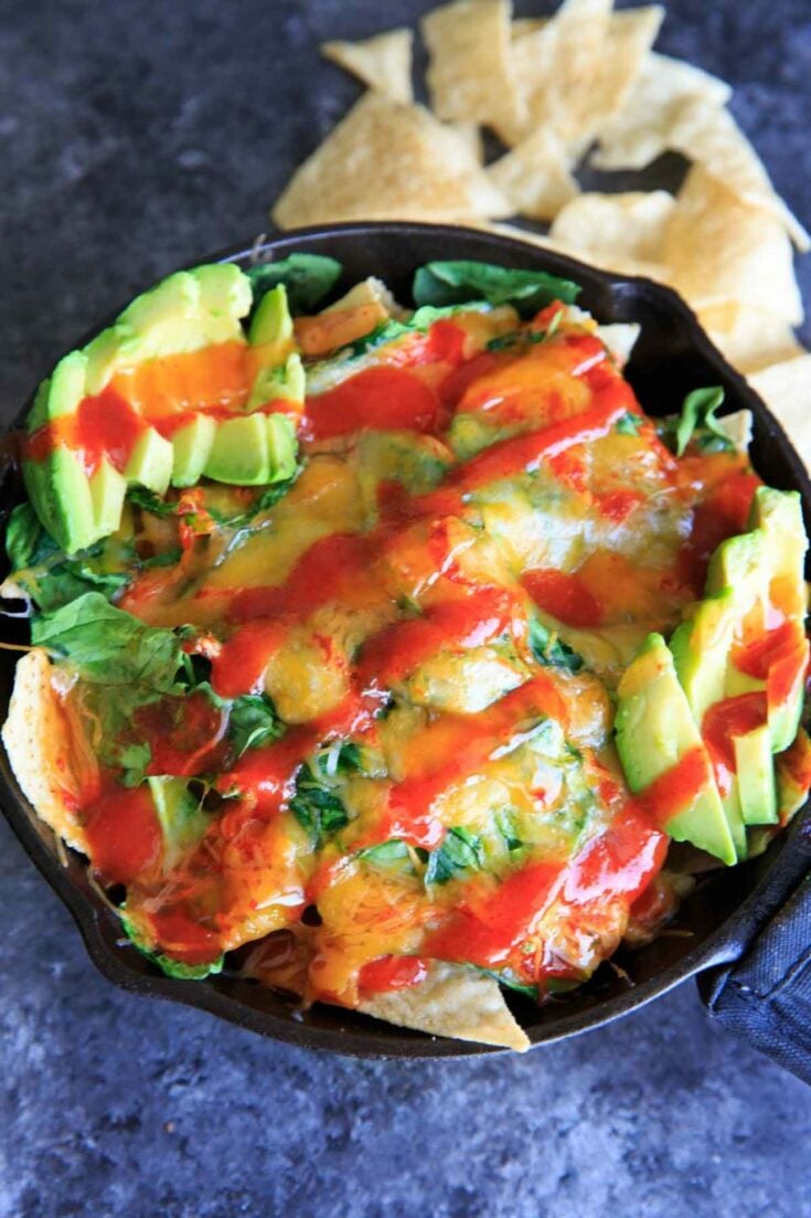 Oven-baked spinach nachos in a cast iron skillet. A great party snack, meal for 2 (or 1!) that has a little extra nutrition with greens.