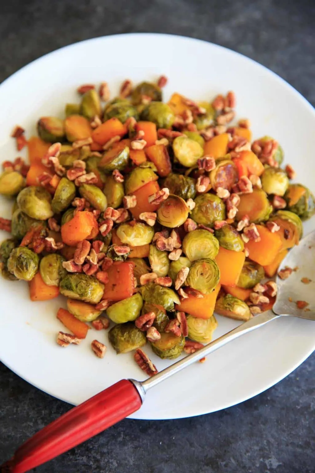 Maple Roasted Brussels Sprout and Butternut Squash with crushed pecans and dried cranberries. A perfect appetizer or side for holiday or fall dinners.