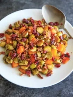 Maple Roasted Brussels Sprout and Butternut Squash with crushed pecans and dried cranberries. A perfect appetizer or side for holiday or fall dinners.