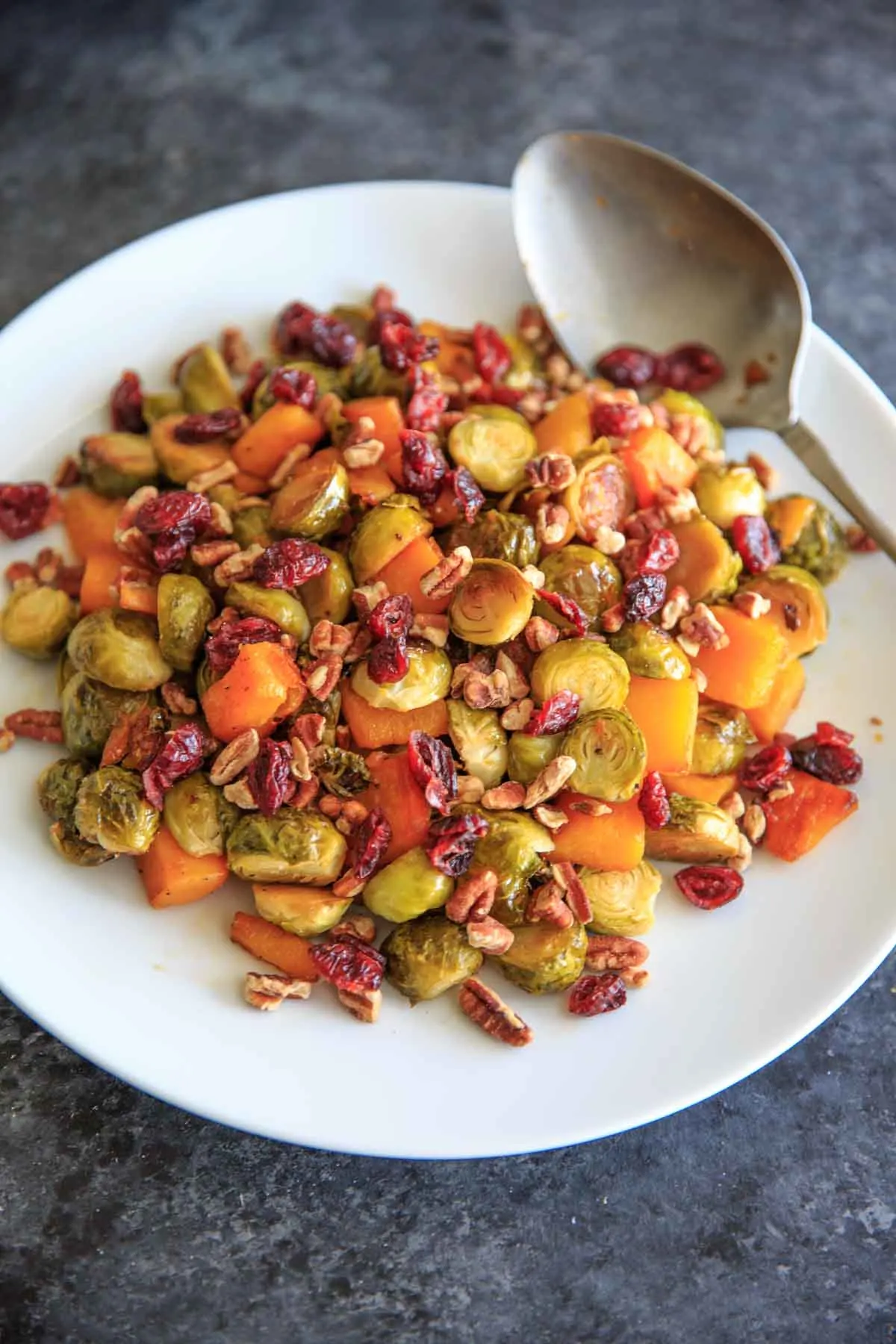 Maple Roasted Brussels Sprout and Butternut Squash with crushed pecans and dried cranberries. A perfect appetizer or side for holiday or fall dinners.