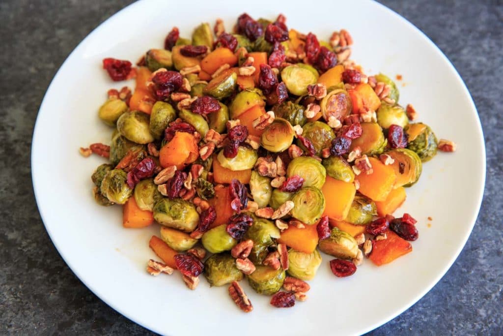 Maple Roasted Brussels Sprout and Butternut Squash with crushed pecans and dried cranberries. A perfect appetizer or side for holiday or fall dinners.