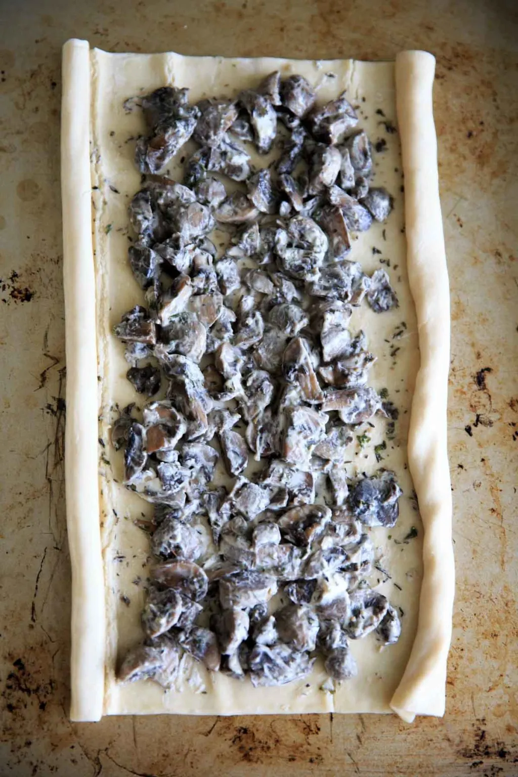 mushrooms spread out on puff pastry sheet before rolling into palmiers and baking