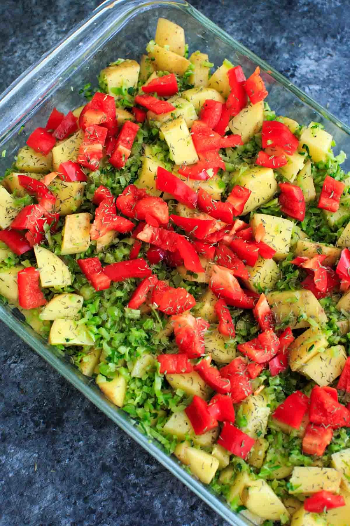 Potatoes, broccoli, bell pepper and spices in a casserole pan