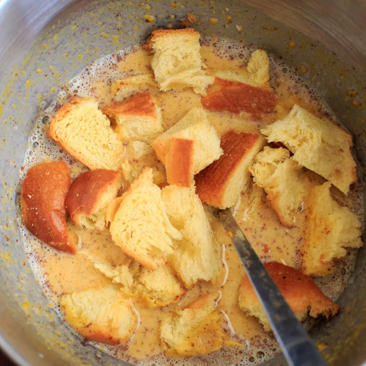 challah bread in bowl mixing into the egg mixture