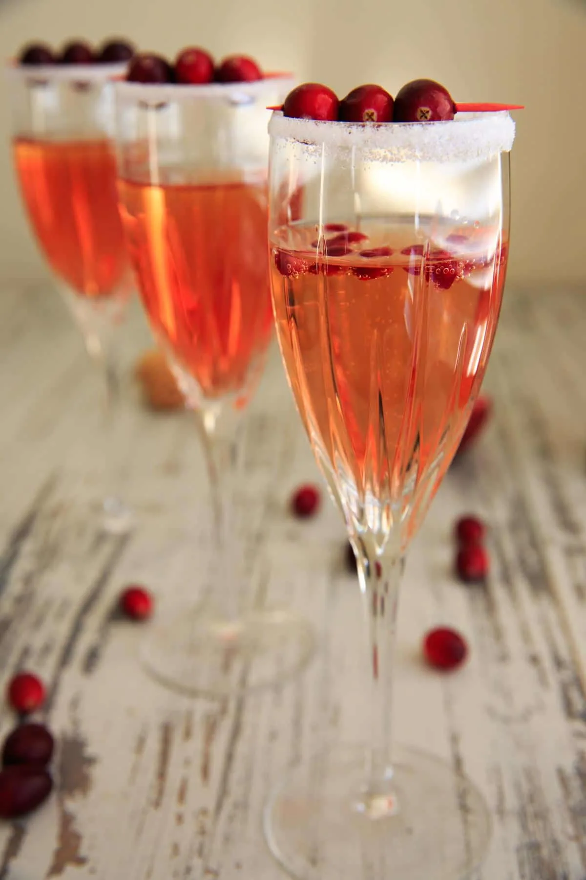 3 decorated glasses of the cranberry prosecco with cranberries on toothpick resting on top