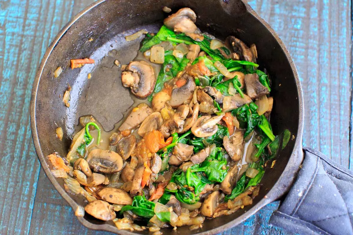 sautéing the veggies down in a cast iron pan for the ultimate vegan breakfast sandwich