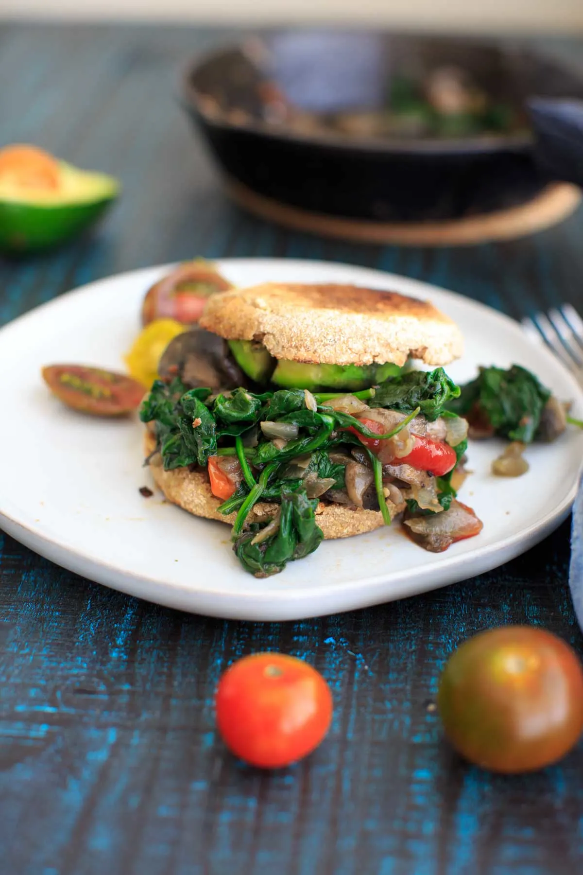 Ultimate Vegan Breakfast Sandwich on an English muffin on white plate with blue background