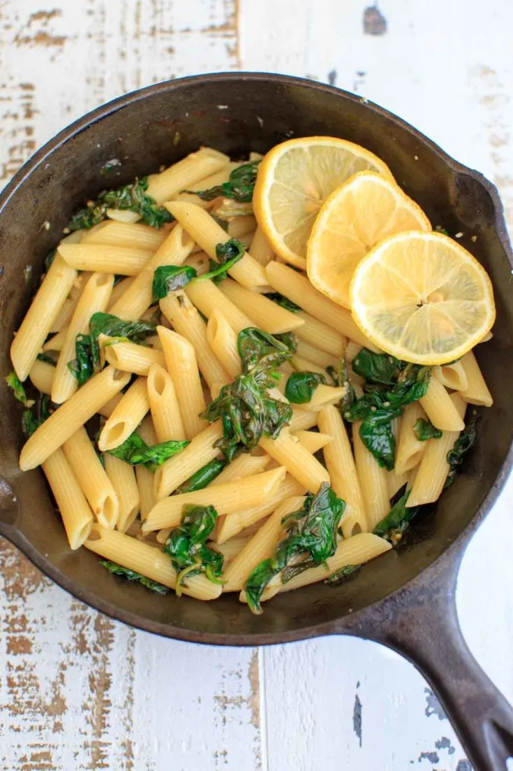 Lemon Spinach Pasta with lemon slices in a cast iron pan