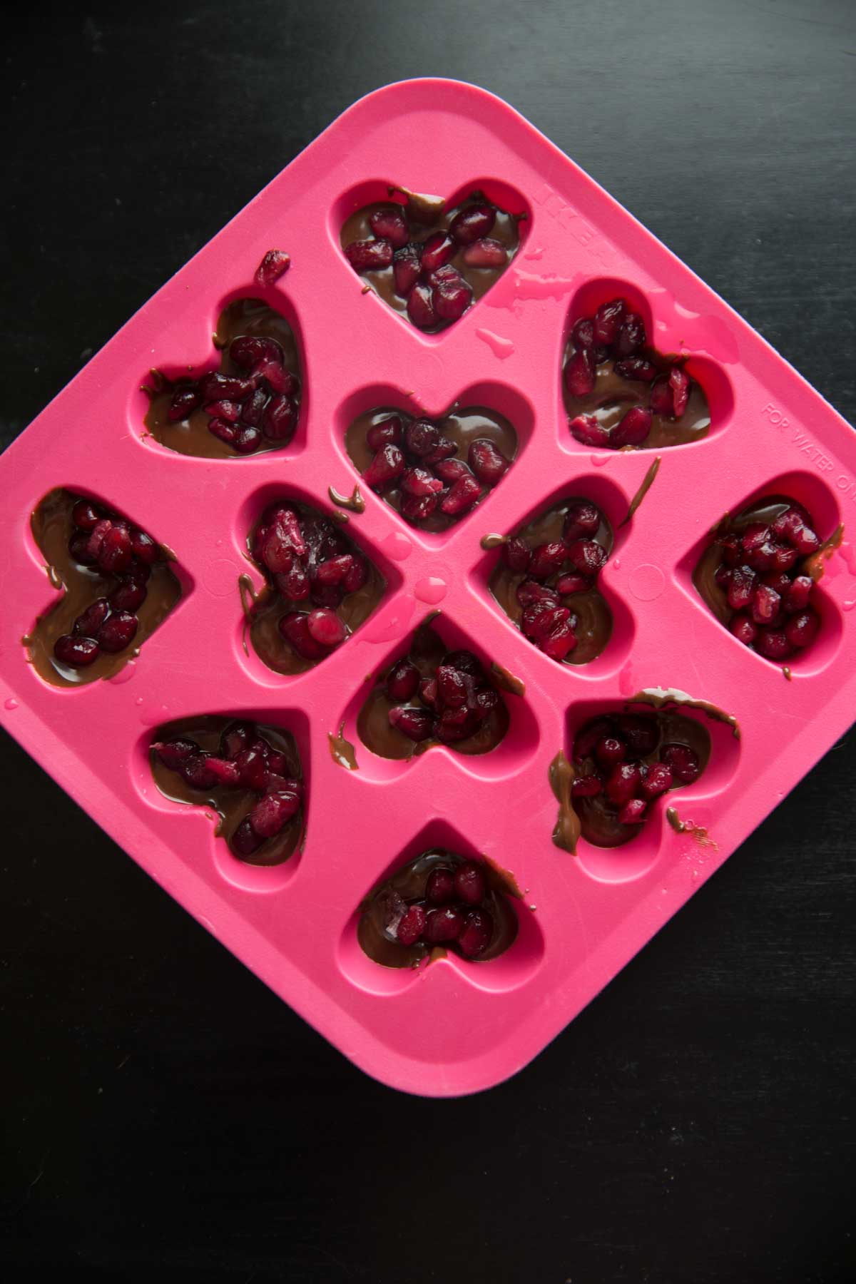Chocolate Pomegranate Candy Recipe - melted chocolate in candy mold with pomegranate seeds