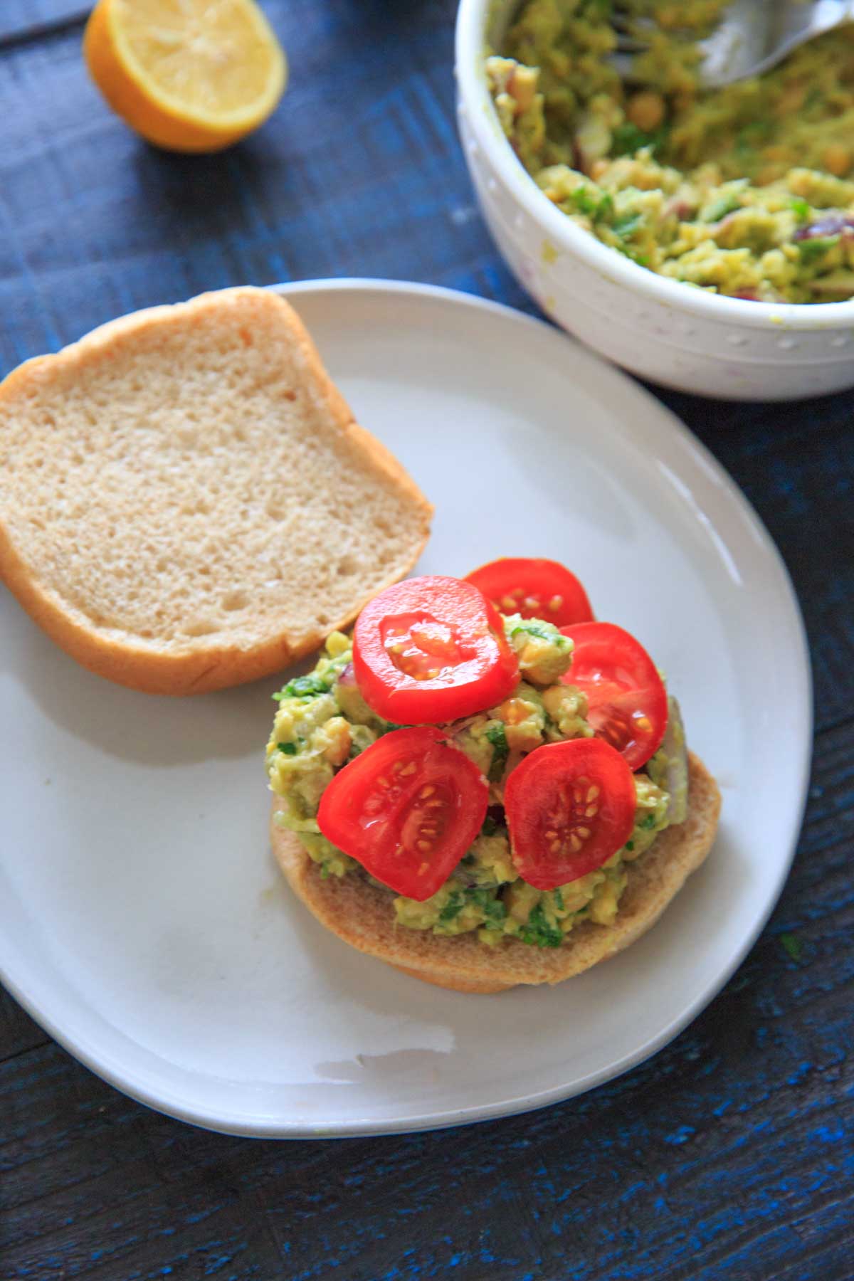 Smashed Avocado and Chickpea Salad on a bun with tomato