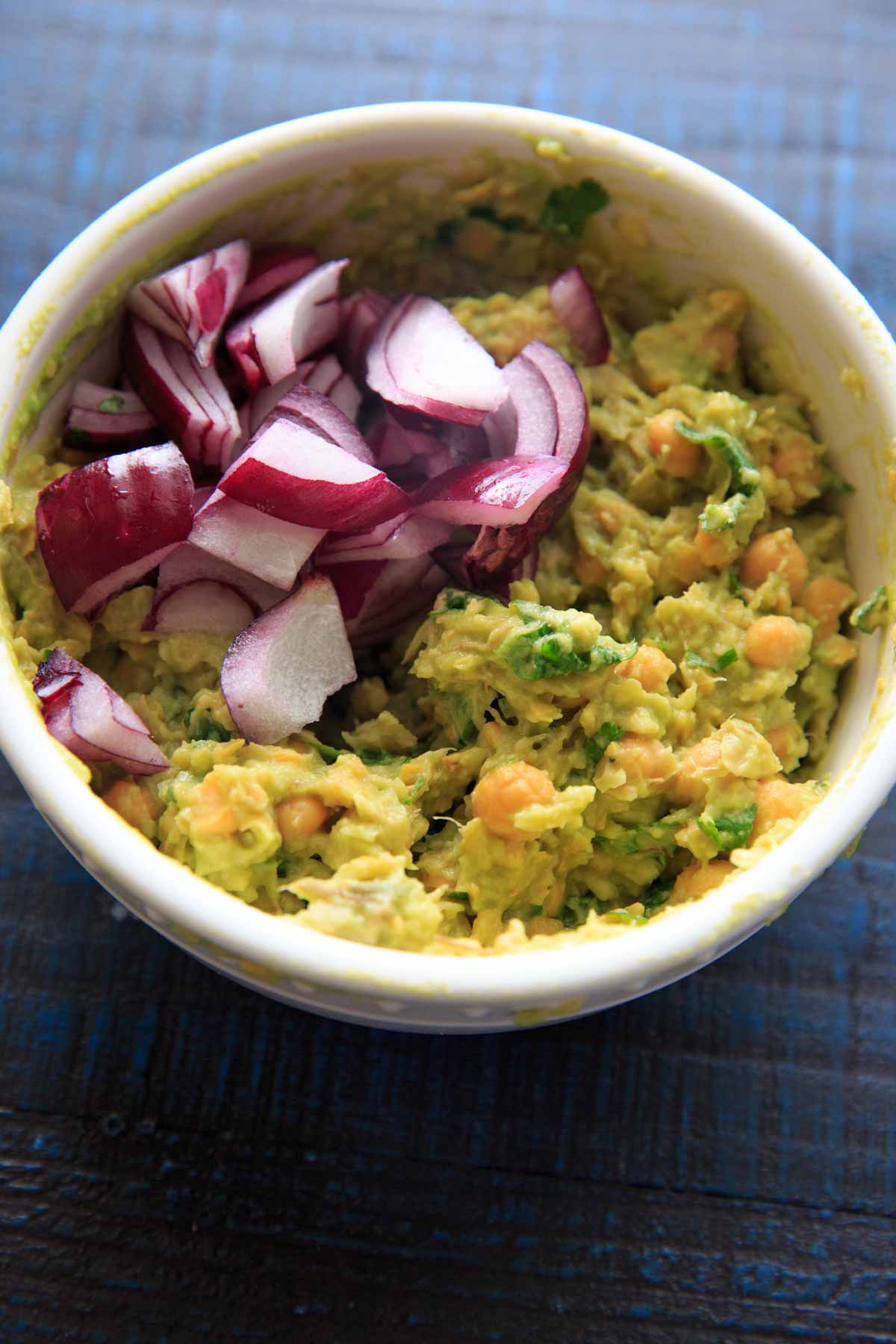 Smashed Avocado and Chickpea Salad in a bowl with red onion