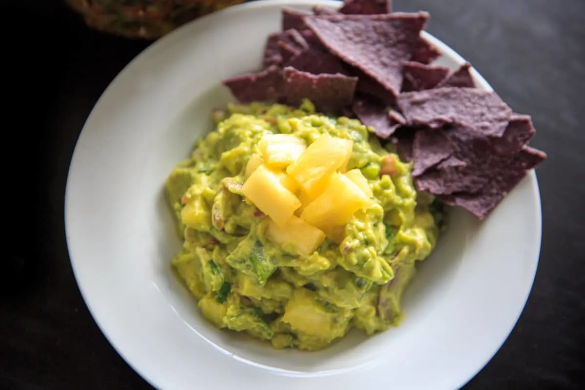 Pineapple Jalapeno Guacamole on white plate with blue chips on side