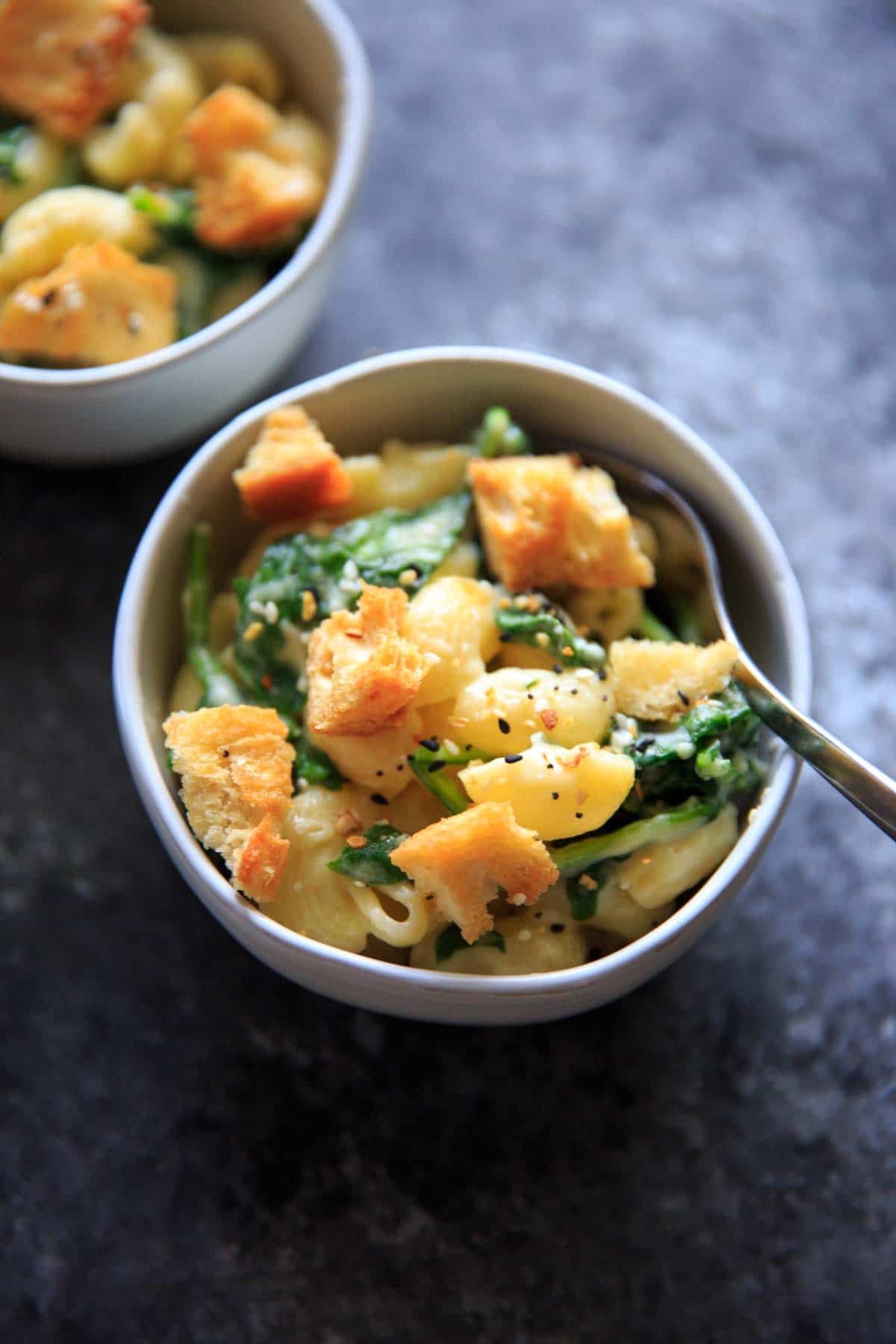 bowl of white cheddar macaroni with spinach and croutons