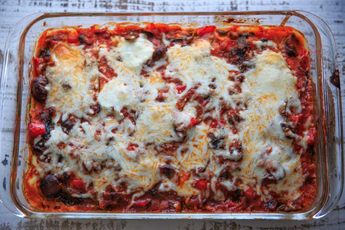 zucchini noodle vegetable lasagna in clear baking dish topped with cheese