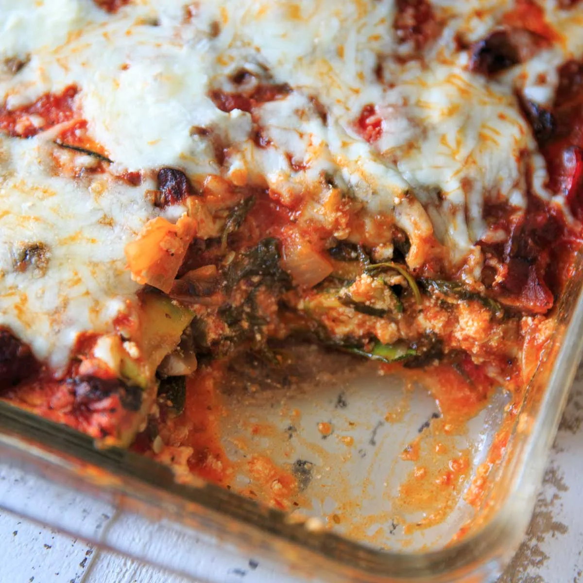 a corner piece missing from the casserole dish of gluten-free zucchini noodle vegetable lasagna