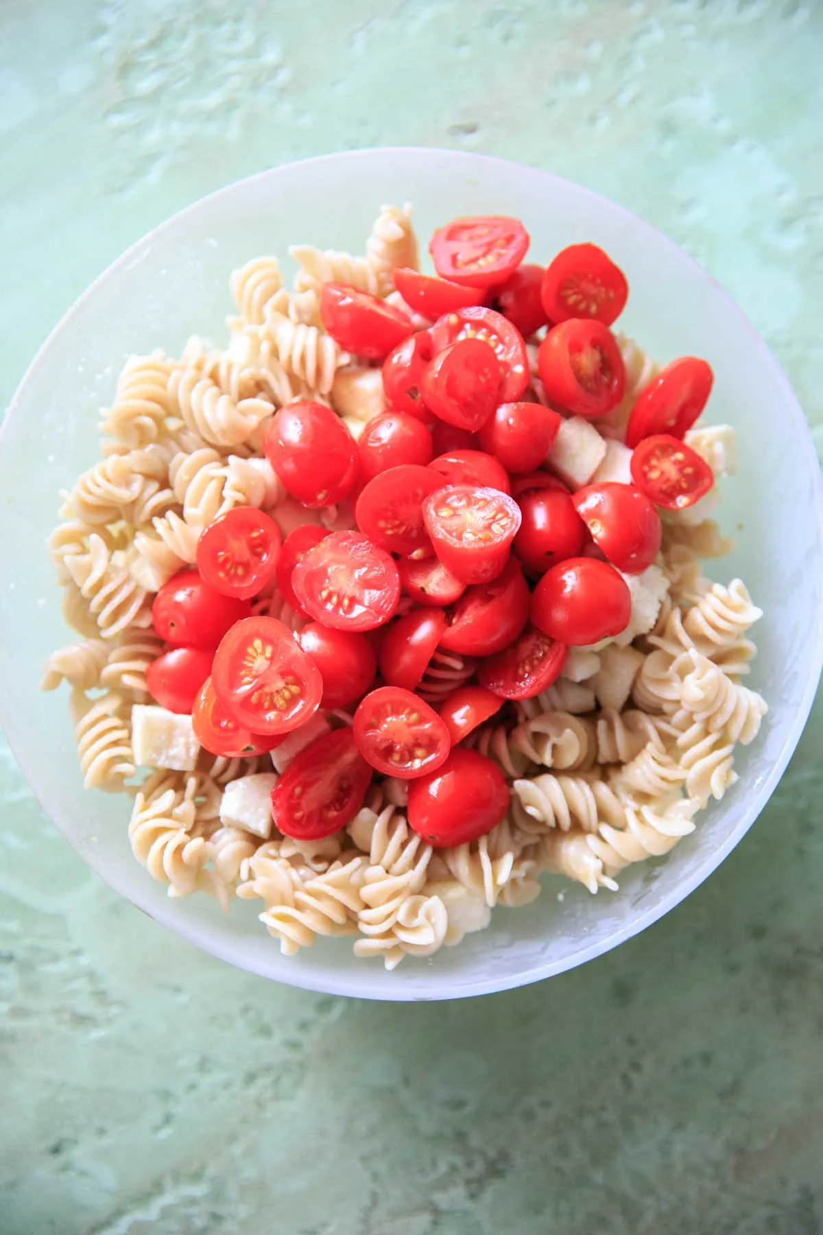 tomatoes and mozzarella on cooked pasta in bowl