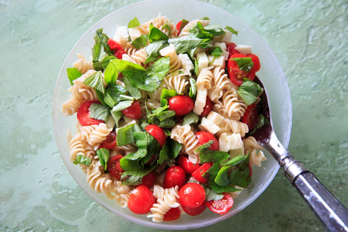 Caprese Pasta Salad in bowl with serving spoon