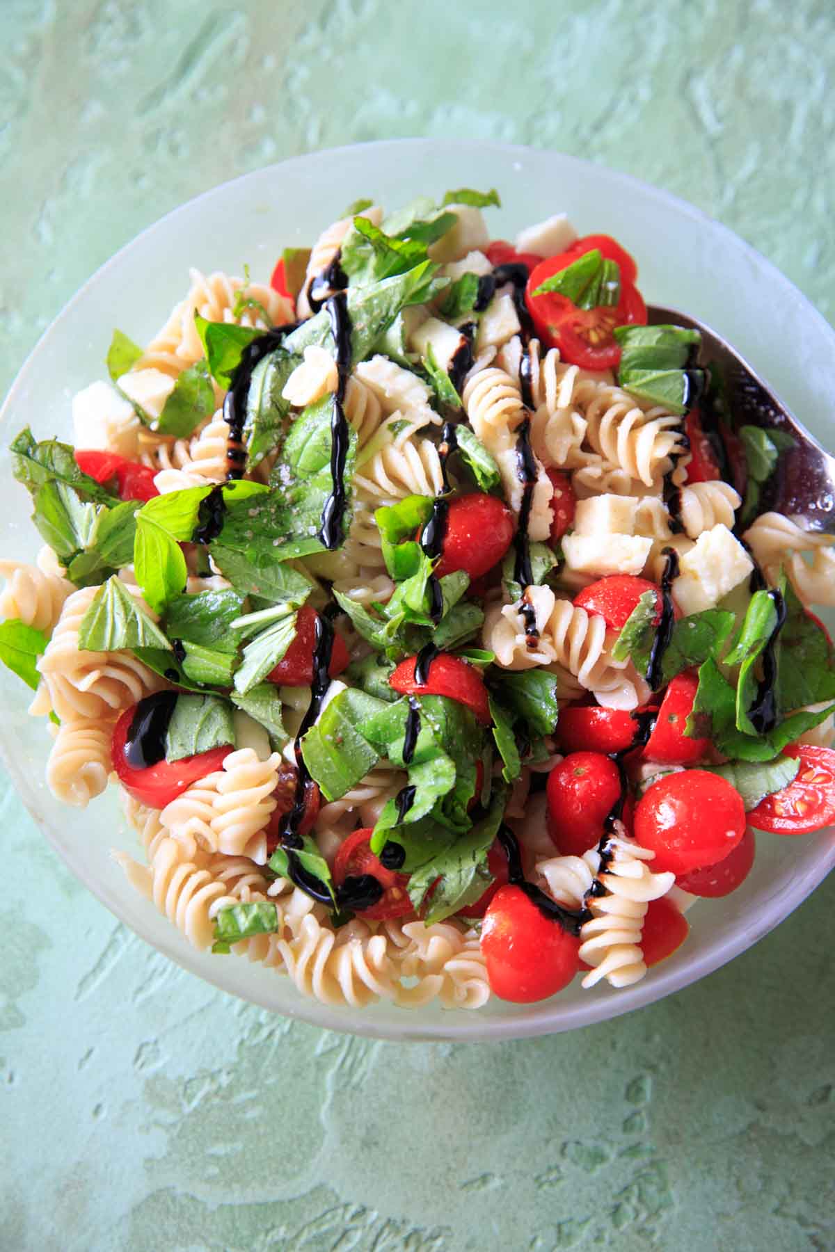 Caprese Pasta Salad - Tomatoes, basil, mozzarella, balsamic and olive oil on pasta in bowl