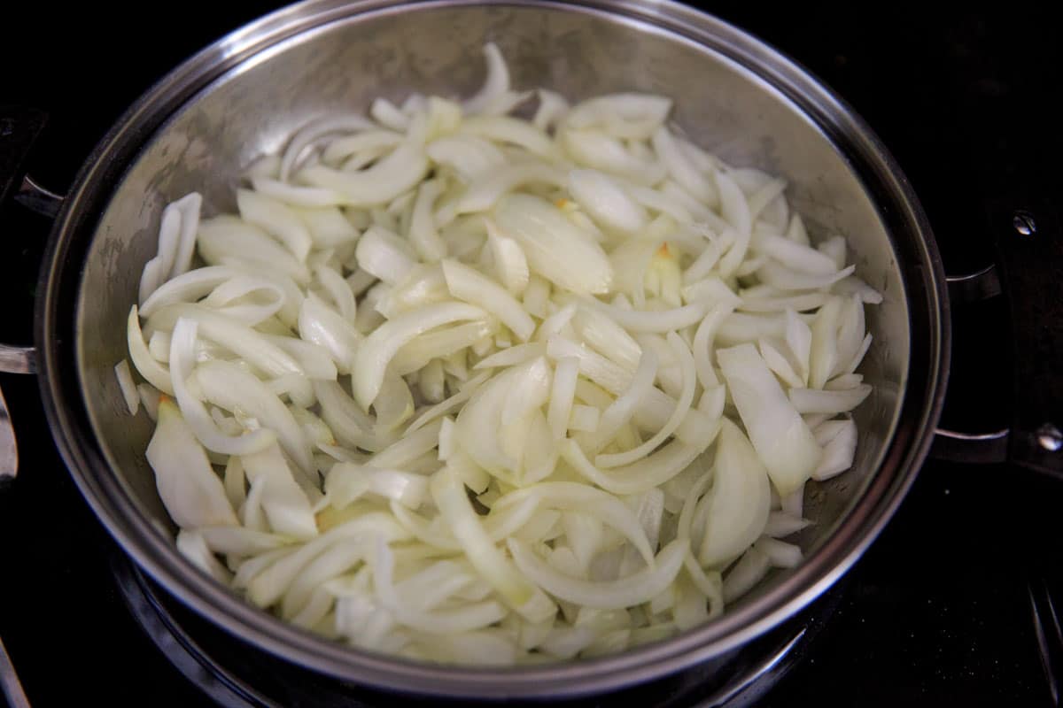 step 1 how to caramelize onions - sliced onion in pan with oil and butter