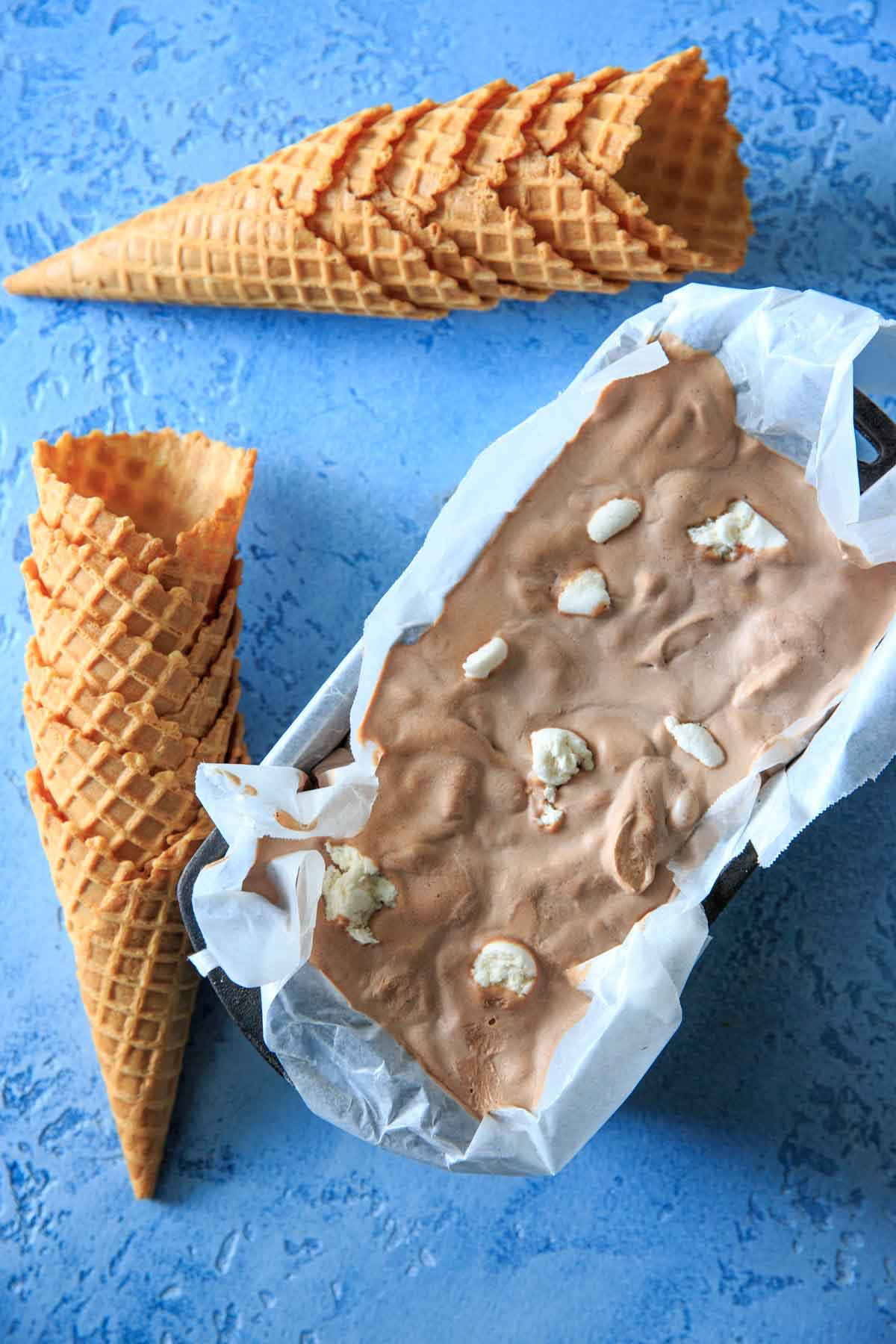 Hot chocolate ice cream frozen with stacked ice cream cones laying next to it