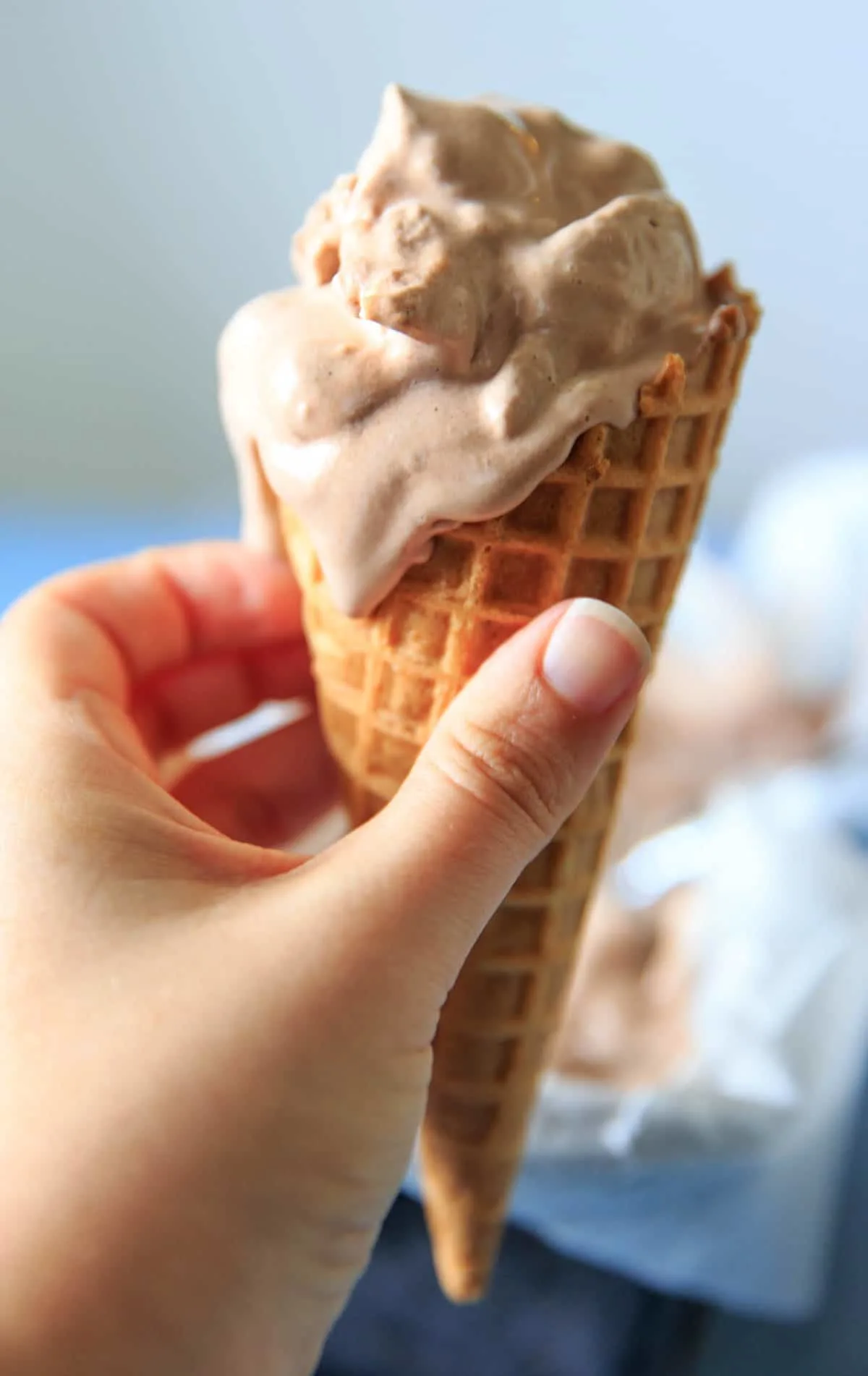hot chocolate ice cream in ice cream cone held in hand slightly melted