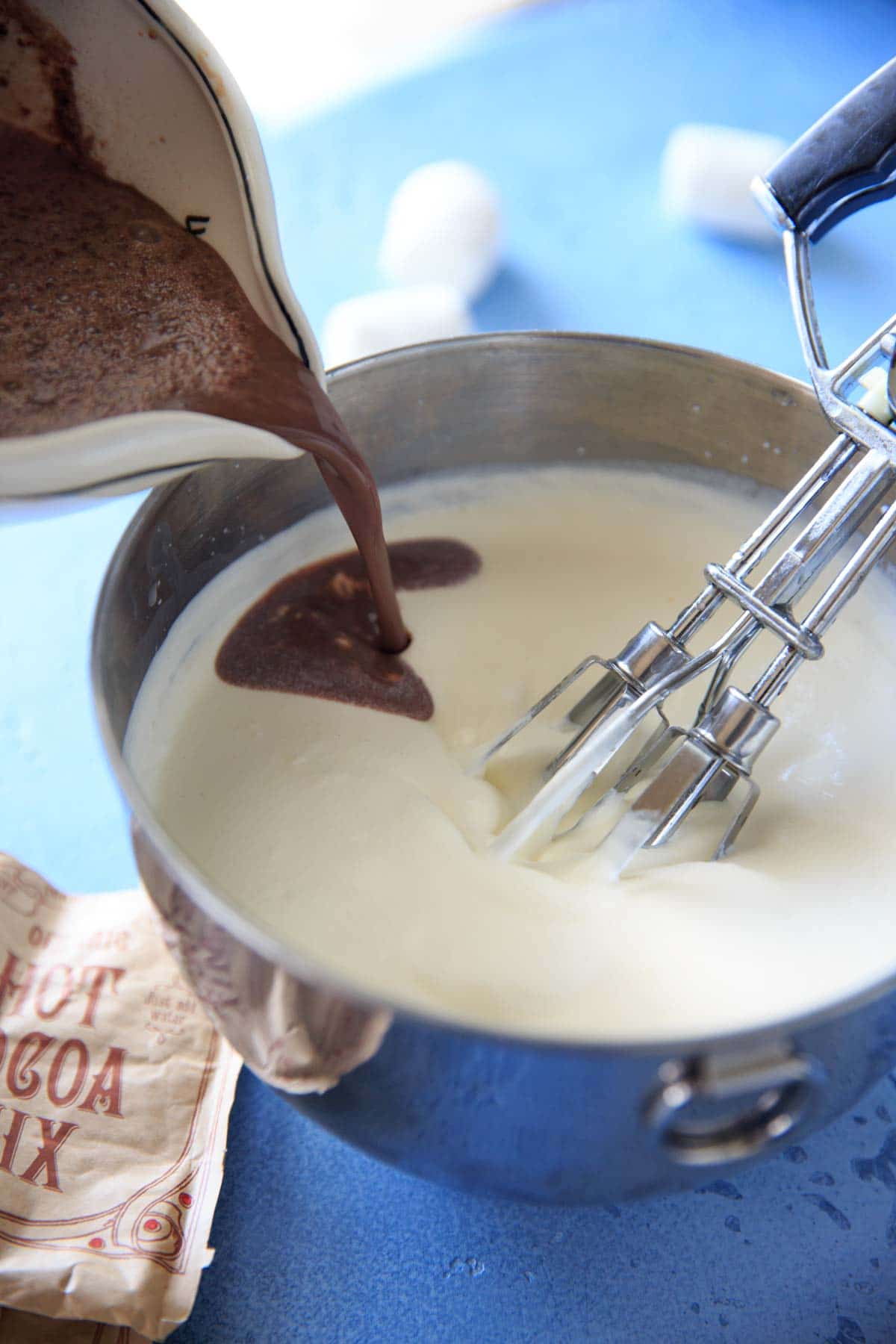 Pouring the hot chocolate and sweetened condensed milk into the whipped whipping cream