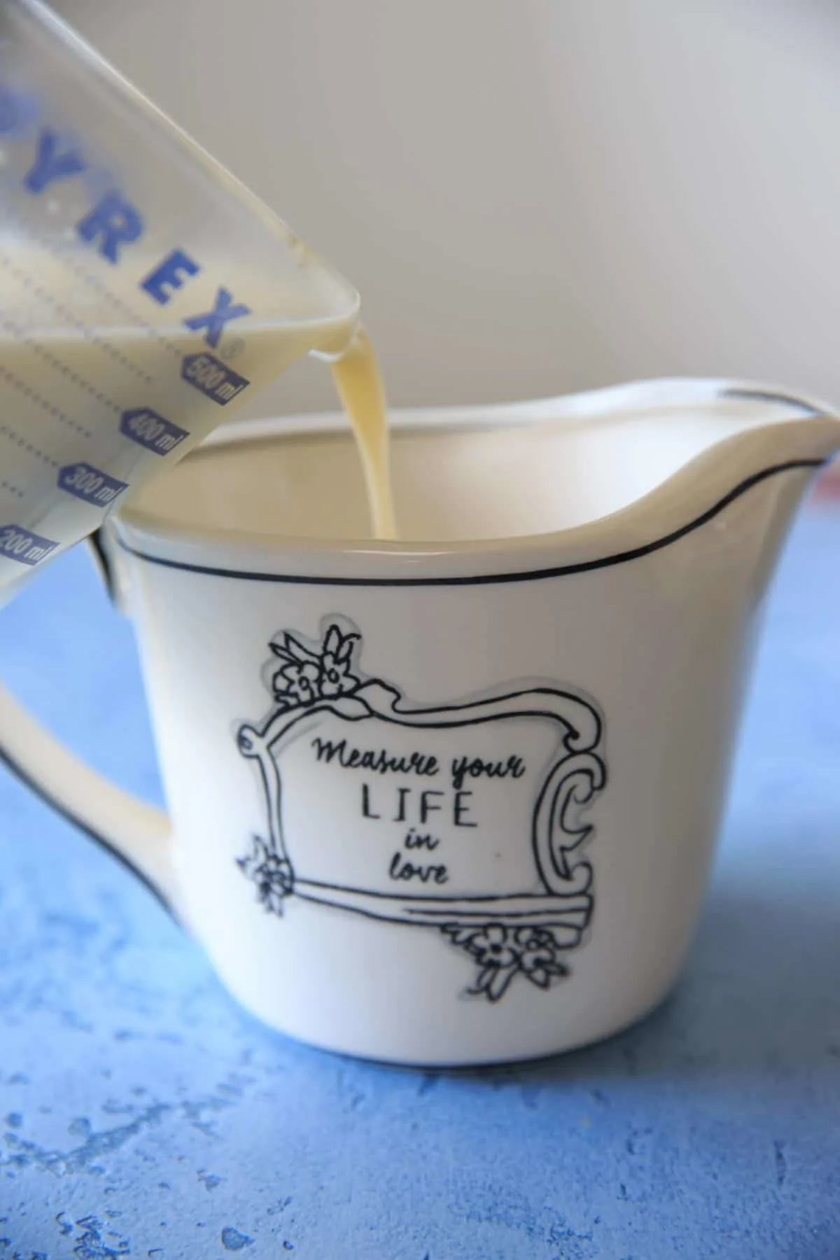 pouring homemade sweetened condensed milk into a measuring cup that says "measure your life in love"